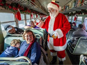 A young boy hides behind the seat as Santa Claus greets passengers on the Christmas train at Exporail's Railway Christmas in St-Constant Nov. 26, 2022.