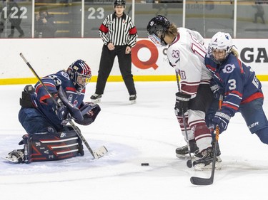 Metropolitan Riveters Sarah Foster, right, bumps Montreal Force's Deziray De Sousa off the puck in front of goalie Rachel McQuigge during the Force's first Premier Hockey League home game in Verdun on Saturday, Nov. 26, 2022.