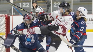Montreal Force's Deziray De Sousa is knocked off her skates by Metropolitan Riveters' Sarah Foster in front of goalie Rachel McQuigge during the Force's first Premier Hockey League home game in Verdun on Nov. 26, 2022.