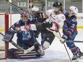 Montreal Force's Deziray De Sousa is knocked off her skates by Metropolitan Riveters' Sarah Foster in front of goalie Rachel McQuigge during the Force's first Premier Hockey League home game in Verdun on Saturday, Nov.  26, 2022.