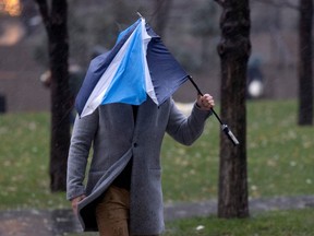 A pedestrian gives up on his broken umbrella as wind and rain begin to build in Montreal on Wednesday, Nov. 30, 2022.