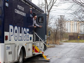 A police investigator looks out from the command post at the scene where a man's body was found in Dorval.