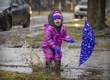 Two-year-old Blake Preston jumps in a puddle while waiting with her mother Jessica Kirzner to pick up her big brother after school in Pointe-Saint-Charles on Nov. 30, 2022.