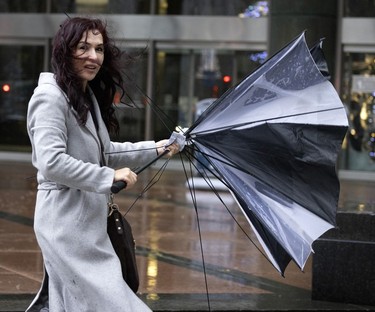 Turkish tourist Dilek Erguven gives up on her broken umbrella as wind and rain begin to build in Montreal on Nov. 30, 2022.