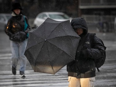 A pedestrian tries to secure his umbrella while walking along Jean-Talon St. in Montreal on Wednesday Nov. 30, 2022.