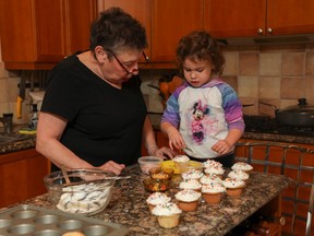 A grandmother and child frost cupcakes.