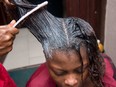 A hairdresser applies hair relaxer cream: "The risk posed by chemical hair straighteners is probably pretty small, especially for women who only use them occasionally," Christopher Labos writes.