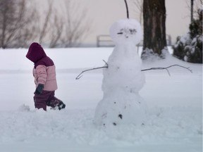 A young girl gets a few minutes of fresh air while making a snowman in the park with her father in 2020.