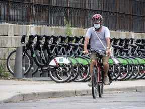 A cyclist wearing a mask rides past a row of Bike Share Toronto rental bikes during the COVID-19 pandemic on July 27, 2020.