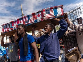 Demonstrators carry a coffin covered with U.S., Canadian and French flags and pictures of politicians as they protest on Jean-Jacques Dessalines Day in Port-au-Prince, Haiti, on October 17, 2022.