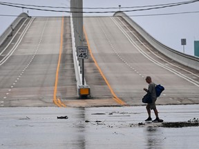 A man carrying personal belongings walks in a flooded street after Hurricane Nicole's landfall in Florida Nov. 10, 2022. Nicole was downgraded to a tropical storm after making landfall.