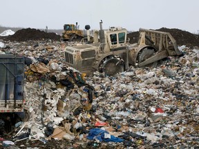 Workers use a Trashmaster to help offload a large truck as they build layers of dumped garbage at the BFI Usine de Triage Lachenaie in Terrebonne in 2008.