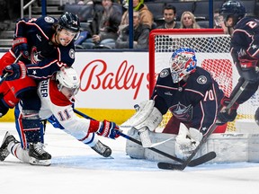 Canadiens right wing Brendan Gallagher (11) shoots the puck as Columbus Blue Jackets center Cole Sillinger (34) knocks him down in front of Columbus Blue Jackets goaltender Joonas Korpisalo (70) in the second period at Nationwide Arena in Columbus, Ohio, on Nov. 17, 2022.