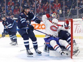 Canadiens centre Nick Suzuki (14) slides into Winnipeg Jets goaltender Connor Hellebuyck (37) after his first period goal at Canada Life Centre in Winnipeg on Thursday, Nov. 3, 2022.