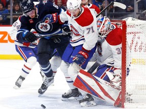 The Winnipeg Jets’ Pierre-Luc Dubois and the Canadiens’ Jake Evans look for the puck in front of Montreal goalie Samuel Montembeault during second period of Thursday night’s game at the Canada Life Centre.