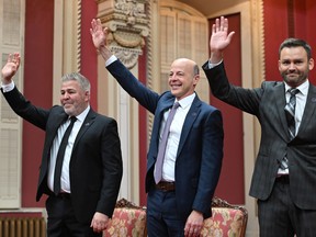 Parti Québécois Leader Paul St-Pierre Plamondon, right, and PQ MNAs Joël Arseneau, centre, and Pascal Bérubé wave to applauding supporters and family before being sworn in during a ceremony at the legislature in Quebec City, Friday, Oct. 21, 2022.