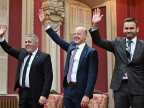 Parti Québécois Leader Paul St-Pierre Plamondon, right, PQ MNAs Joël Arseneau, centre and Pascal Bérubé wave to applauding supporters and family at a ceremony at the legislature in Quebec City, Friday, Oct. 21, 2022. The three swore allegiance to the people of Quebec but not to King Charles III.