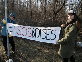 Normand Lapointe, left, and Geneviève Lussier, members of Save Fairview Forest group, set up a banner next to the wooded area on Saturday Dec. 10, 2022. The group was protesting for 107th consecutive weekend.