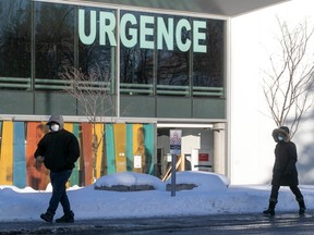 Wearing their masks, people walk past the emergency entrance of Maisonneuve-Rosemont Hospital on Jan. 20, 2021.