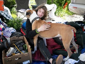 Alexandre Poulin hugs his dog Mowglie at makeshift campground at the bottom of Iberville near Notre-Dame May 25, 2022.