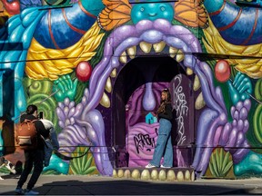 Shana Nirmala poses for her boyfriend, Quentin Fourie, in front of this colourfully painted building on the corner of St-Laurent Blvd. and Marie-Anne St. Nov. 8, 2022.