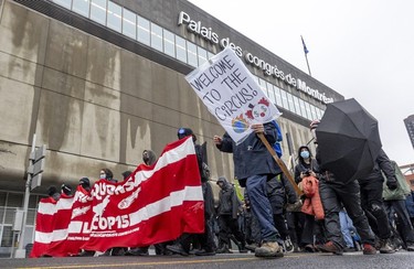 Anti-capitalist demonstrators walk past the Palais des congrès in Montreal during the COP15 conference on Dec. 7, 2022