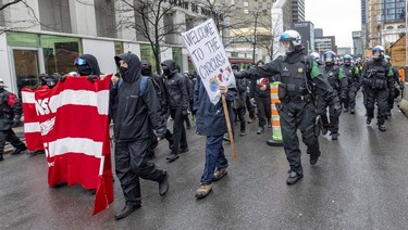 A police officer pushes an anti-capitalist demonstrator back into his group as they walk through the streets of Montreal protesting the COP15 conference on Dec. 7, 2022