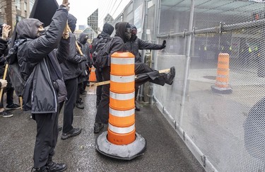 Anti-capitalist demonstrators kick the security fence around the Palais des congrès during the COP15 conference in Montreal on Dec. 7, 2022