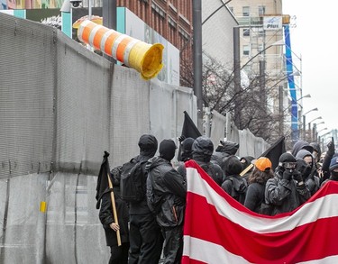 Anti-capitalist demonstrators throw an orange cone over the security fence surrounding the Palais des congrès in Montreal on Dec. 7, 2022