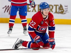 Montreal Canadiens winger Cole Caufield grimaces after taking a hard check by Calgary Flames' Trevor Lewis during second period in Montreal on Dec. 12, 2022.