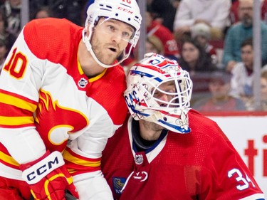 Canadiens' Jake Allen has his goalie mask knocked sideways as Calgary Flames' Jonathan Huberdeau skates through the goal crease during second period of a National Hockey League game in Montreal Monday Dec. 12, 2022.