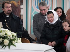 The mother and father of Mariia Legenkovska -- Galyna Legenkovska (white scarf) and Andrii Lehenkovskyi (grey sweather) -- pray next to the casket of their seven-year-old child during her funeral on Wednesday Dec. 21, 2022. Mariia died after being hit by a car last week as she was walking to school.