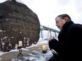 Ken Quinn of the St. Patrick's Society of Montreal lights a candle in memory of thousands of Irish famine victims buried in a cemetery under the Black Rock monument near the Victoria Bridge, on Wednesday, Dec. 21, 2022.
