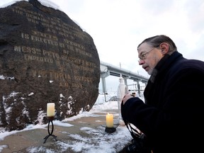 Ken Quinn of the St. Patrick's Society of Montreal lights a candle in memory of thousands of Irish famine victims buried in a cemetery under the Black Rock monument near the Victoria Bridge, on Wednesday, Dec. 21, 2022.