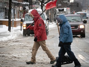 Holding on to their shovels, Montrealers cross Park Ave. on Friday, Dec. 23, 2022.