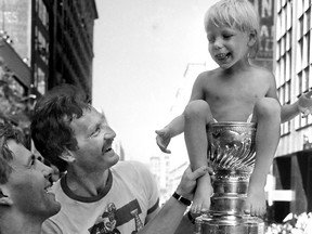 During the Stanley Cup Parade along downtown Ste-Catherine St. in Montreal on May 26, 1986, Montreal Canadiens captain Mats Naslund holds onto his 3-year-old son, Daniel, while teammate Larry Robinson steadies the Cup.