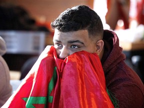 Zoubair Rossaine buries his face in a Moroccan flag as watches France play Morocco in the World Cup semi final at Cafe Lina, in Montreal, on Wednesday, Dec. 14, 2022.