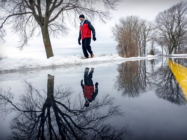 Zoltan Szecsenyi detours around a puddle caused by melting snow on the winter walking path along the lakeshore in the Lachine borough of Montreal Friday Dec. 30, 2022. Montreal is expecting a week of unseasonably warm weather.