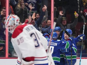 Canucks players celebrate in front of Canadiens goalie Samuel Montembeault after Elias Pettersson scored in overtime for a 7-6 victory Monday night at Rogers Arena in Vancouver.