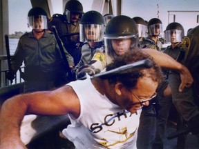 A Sûreté du Québec officer clubs a retreating protester on a lift bridge in St-Louis-de-Gonzague that had been blocked by Châteauguay protesters on Aug. 12, 1990.