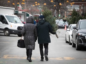 A couple walks away with their Christmas tree at Atwater market Dec. 11, 2022.