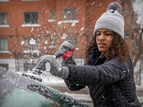 Sarah-Lisa Ladouceur scrapes ice off her windshield on Thursday after Montreal was hit with a combination of ice pellets, snow and freezing rain.