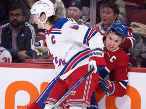 Canadiens captain Nick Suzuki is crunched along the boards by Rangers defenceman Jacob Trouba Thursday night at the Bell Centre. Suzuki has been struggling lately, with only one goal and one assist in his last 13 games.