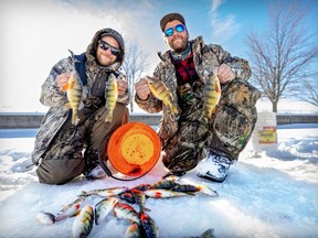 Brothers Mathieu, right, and Brendan Duheme, from Valleyfield, show off their catch after fishing for perch on the ice in the canal at Ste-Anne-de-Bellevue Jan. 16, 2023.