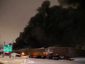 A black plume of smoke rises from a fire near Highway 13 in Montreal’s St-Laurent borough on Monday Jan. 23, 2023.