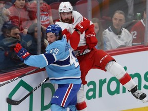 Red Wings' Filip Hronek goes up into the boards trying to hit Canadiens' Rafael Harvey-Pinard during first-period action at the Bell Centre Thursday night.