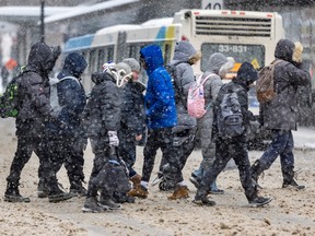 Pedestrians cross Guy St. at Ste-Catherine St. on a snowy Montreal day, Jan. 30, 2023.