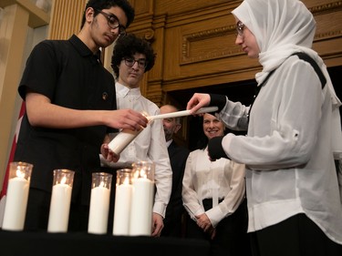 Students Amir Boudinar, left, Abdelrahman Badreldin, centre, and Rokaya Hussain light a candle in front of Montreal Mayor Valérie Plante at city hall on Friday, Jan. 27, 2023, to commemorate the Quebec city mosque killings of 2017.