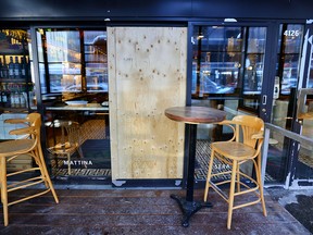 Plywood covers the door of Café Gentile after shots were fired at the coffee shop on Ste-Catherine St. Jan. 31, 2023.
