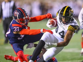 Hamilton Tiger-Cats running-back Wes Hills breaks a tackle by Montreal Alouettes Wesley Sutton to score a touchdown during first half in Montreal on Sept. 23, 2022.